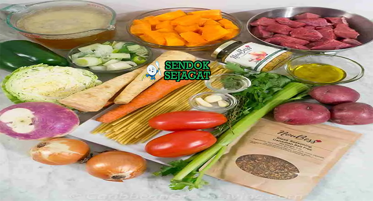 Bahan-bahan segar resep Soup Joumou Haiti: labu kuning potong dadu, daging sapi berlemak, wortel, kentang, kol, plantain, bawang putih, epis Haiti, jahe, dan rempah aromatik