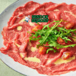 Carpaccio daging sapi mentah iris tipis saus mustard pecorino romano caper rocket lemon piring Piemonte Italia