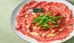 Carpaccio daging sapi mentah iris tipis saus mustard pecorino romano caper rocket lemon piring Piemonte Italia