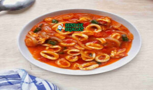 Cumi Saus Padang Khas Jakarta – Pedas Gurih Manis Legit ala Warteg Cumi saus Padang khas Jakarta ala warteg, cumi empuk kenyal disiram saus merah pedas manis gurih, nasi hangat, kerupuk, lalapan timun kemangi, sajian rumahan autentik