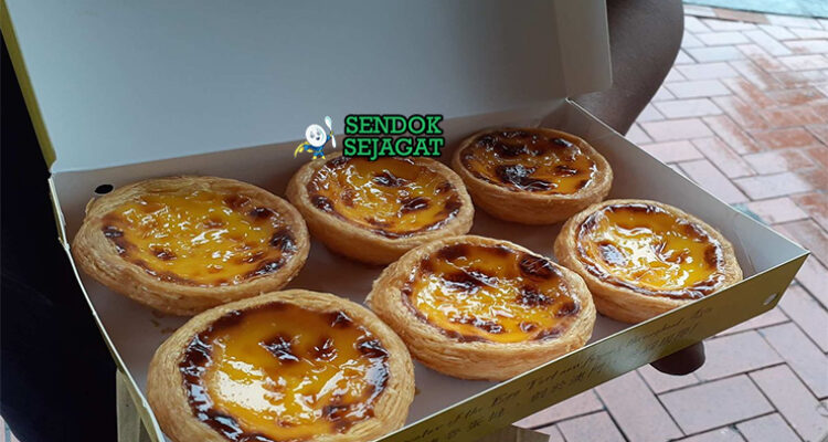 Egg tart Makau asli dengan kulit puff pastry renyah, custard telur kuning lumer, karamel hangus di atas, disajikan di piring putih
