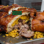 Lechona babi panggang utuh kulit renyah nasi kuning achiote arepas yuca piring Tolima Kolombia