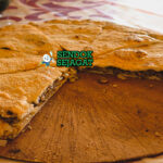 Madfouna roti isi daging Berber panggang golden kecokelatan potong irisan teh mint piring Maroko Sahara Rissani