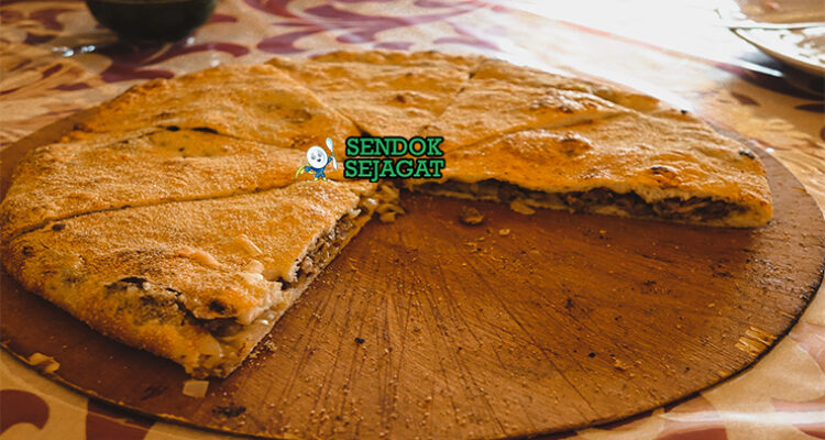 Madfouna roti isi daging Berber panggang golden kecokelatan potong irisan teh mint piring Maroko Sahara Rissani