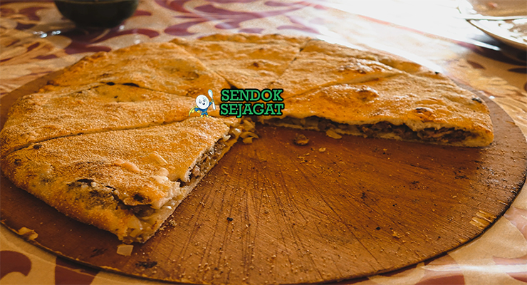 Madfouna roti isi daging Berber panggang golden kecokelatan potong irisan teh mint piring Maroko Sahara Rissani