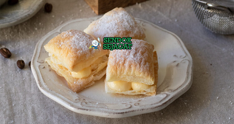 Miguelitos de La Roda siap saji: pastry puff renyah berlapis, diisi custard krim vanila lembut, ditaburi gula halus tebal, terlihat menggoda dan flaky