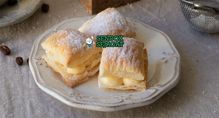 Miguelitos de La Roda siap saji: pastry puff renyah berlapis, diisi custard krim vanila lembut, ditaburi gula halus tebal, terlihat menggoda dan flaky