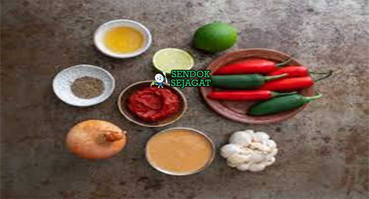 Bahan segar resep beyaynetu Etiopia: kacang kuning kering, lentil merah, collard greens iris, bawang bombay, bawang putih, berbere bubuk, injera segar, minyak sayur di atas meja dapur kayu