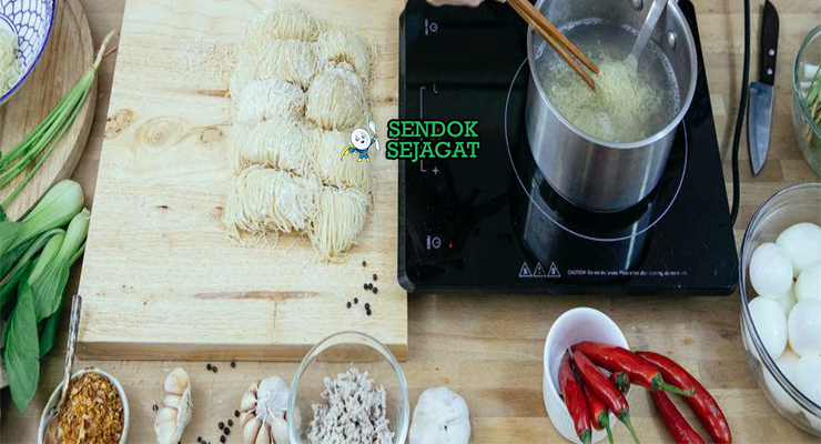 Bahan segar resep cwie mie Malang: mie kuning basah, dada ayam fillet, bawang putih cincang, bawang merah cincang, kecap manis, lada bubuk, kulit pangsit, sawi hijau, bakso sapi di atas meja dapur kayu cerah