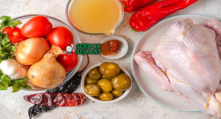 Bahan segar resep kak'ik Guatemala: kalkun potong besar, cabai guajillo kering, tomat matang, bawang bombay, bawang putih, jahe, kentang, wortel, biji coriander, jinten, achiote bubuk di atas meja dapur kayu sederhana