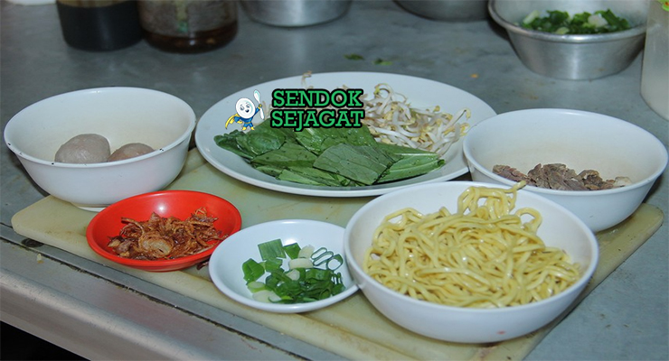 Bahan segar resep mie kocok Bandung: kikil sapi potong, mie kuning basah, tauge, telur ayam, bawang merah, bawang putih, jahe, lengkuas, serai, daun salam di atas meja dapur kayu