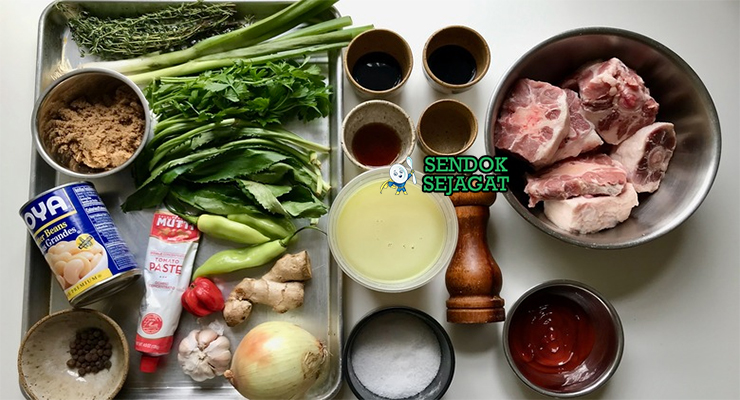 Bahan segar resep oxtail stew Jamaica: ekor sapi potong, cabai Scotch bonnet, daun thyme, allspice berries, bawang putih, jahe, butter beans kaleng, dan rempah Karibia di atas meja dapur