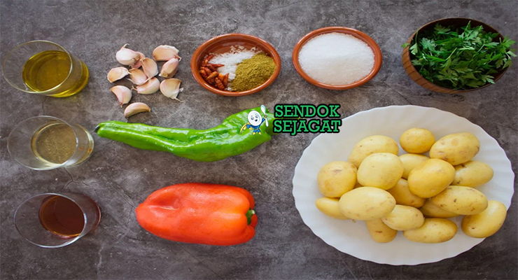 Bahan segar resep papas arrugadas con mojo: kentang kecil utuh, garam laut kasar, cabai merah kering, bawang putih, jinten, paprika, minyak zaitun, cuka, ketumbar, peterseli di atas meja dapur kayu