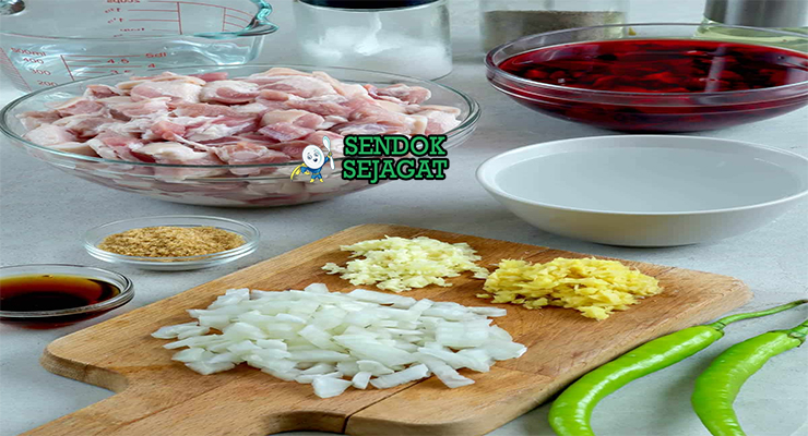 Bahan segar resep pork dinuguan Filipina: daging babi potong dadu, darah babi segar, cuka putih, bawang bombay, bawang putih, jahe, cabai hijau panjang, daun salam di atas meja dapur