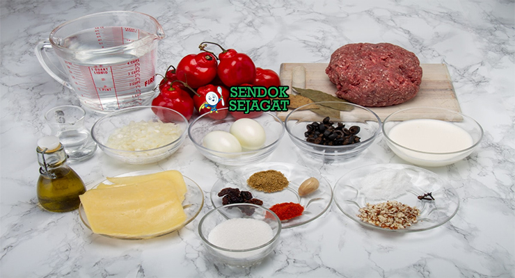 Bahan segar resep rocoto relleno Peru: cabai rocoto utuh merah, daging sapi cincang, keju parut, bawang bombay, bawang putih, tomat, zaitun hitam, kismis, rempah di atas meja dapur kayu