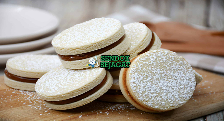 Tumpukan Alfajores khas Chili dengan kue pendek renyah, isi dulce de leche kental mengalir, taburan kelapa parut, tampak manis menggugah selera
