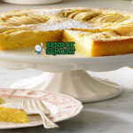 Potongan Apfelkuchen khas Jerman dengan apel segar tenggelam di kue lembut, taburan kayu manis, tampak hangat dan menggugah selera