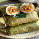 Arem-arem khas Jawa Tengah siap saji: lontong ketan pulen dibungkus daun pisang hijau, potong memperlihatkan isian ayam suwir bumbu kental manis pedas, terlihat gurih hangat dengan uap mengepul