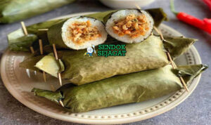 Arem-arem khas Jawa Tengah siap saji: lontong ketan pulen dibungkus daun pisang hijau, potong memperlihatkan isian ayam suwir bumbu kental manis pedas, terlihat gurih hangat dengan uap mengepul