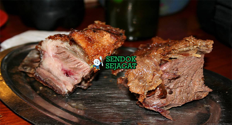 Potongan asado con cuero khas Uruguay dengan kulit renyah keemasan, daging merah muda juicy, disajikan dengan chimichurri hijau segar, chorizo panggang dan kentang al plomo