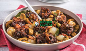 Potongan braised kangaroo tail khas Australia yang empuk terlepas dari tulang, disiram kuah kental gurih berwarna cokelat tua, disajikan dengan kentang tumbuk dan sayur hijau segar