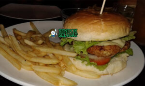 Burger crocodile khas Australia dengan patty daging buaya panggang juicy, alpukat halus, selada segar, irisan tomat, dan saus sweet chili di roti bun hangat