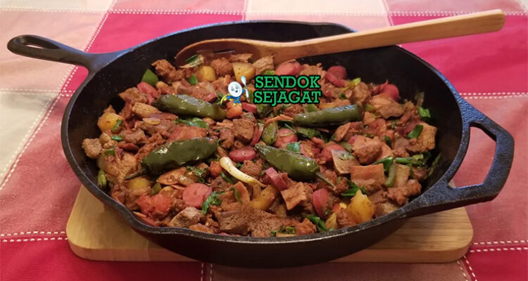 Discada khas Meksiko siap saji: wajan besar berisi tumisan daging sapi, chorizo, bacon, sosis, ayam, paprika merah-hijau, bawang bombay, tomat, cabai, terlihat gurih berapi dengan uap mengepul dan warna cerah