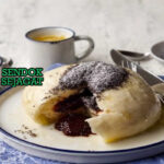 Germknödel Siap Saji Hangat dengan Biji Poppy Germknödel khas Austria dengan dumpling ragi lembut mengembang, isian selai plum meleleh, taburan biji poppy dan gula bubuk, tampak manis hangat menggugah selera