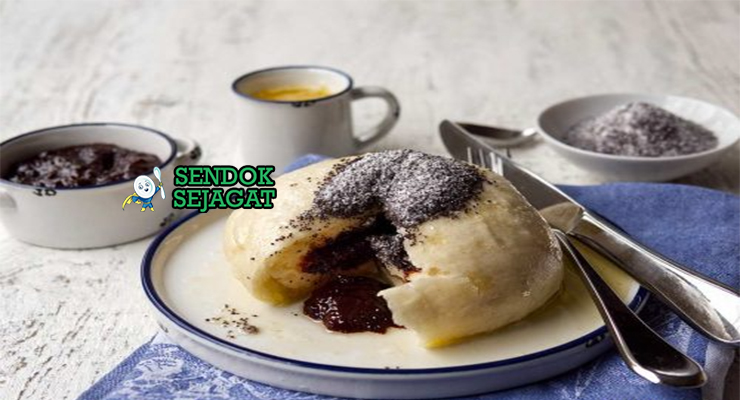Germknödel khas Austria dengan dumpling ragi lembut mengembang, isian selai plum meleleh, taburan biji poppy dan gula bubuk, tampak manis hangat menggugah selera