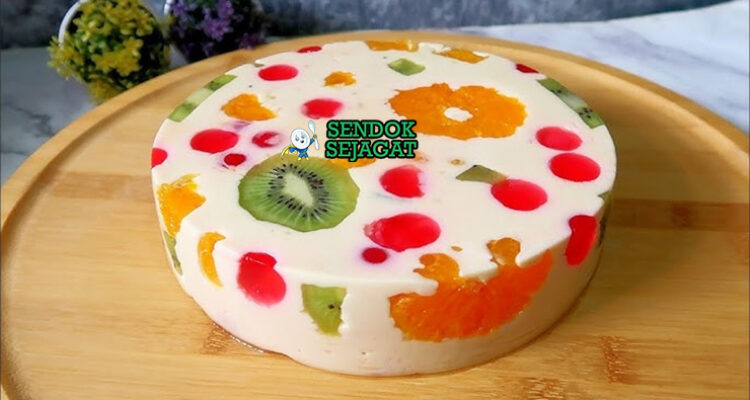 Jelly cake khas Australia siap saji: potongan irisan memperlihatkan lapisan jelly bening warna-warni (merah, hijau, kuning, biru), sponge cake lembut, dan buah segar terperangkap cantik, terlihat segar menggoda di piring putih