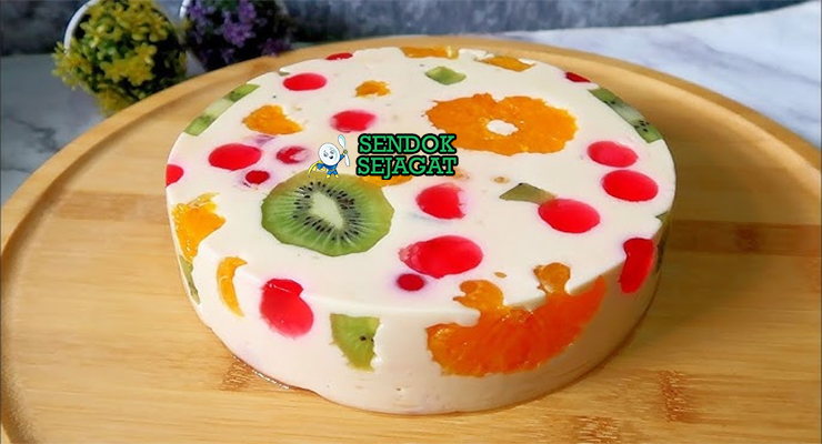 Jelly cake khas Australia siap saji: potongan irisan memperlihatkan lapisan jelly bening warna-warni (merah, hijau, kuning, biru), sponge cake lembut, dan buah segar terperangkap cantik, terlihat segar menggoda di piring putih