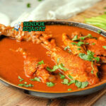 Kak'ik khas Guatemala siap saji: mangkuk sup kalkun kental berwarna merah kecokelatan, potongan daging kalkun empuk, kentang dan wortel lembut, tabur bawang merah iris, daun ketumbar segar, disajikan dengan tortilla jagung hangat dan jeruk nipis, terlihat gurih pedas hangat dengan uap mengepul