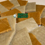 Kocho khas Etiopia siap saji: roti enset tebal kenyal berwarna krem kecokelatan, dipotong segi empat, tekstur padat tapi lembut, terlihat hangat dan menggoda di atas daun pisang Kocho Hangat Segar Dipotong Tebal dengan Tekstur Kenyal