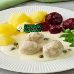Piring Königsberger Klopse khas Jerman dengan bakso daging lembut dalam saus krim putih berisi kapari, disajikan bersama kentang rebus dan bit merah