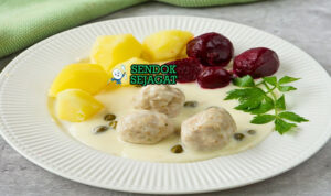 Piring Königsberger Klopse khas Jerman dengan bakso daging lembut dalam saus krim putih berisi kapari, disajikan bersama kentang rebus dan bit merah