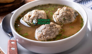 Mangkok Leberknödelsuppe khas Jerman dengan kaldu bening, dumpling hati kenyal, bawang goreng, dan peterseli, tampak hangat gurih menggugah selera