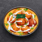 Hidangan Malai Kofta khas India dengan bola keju paneer goreng, saus creamy tomat, dan taburan kasuri methi, tampak lezat dan berwarna