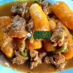 Matoke ya nyama khas Uganda siap saji: pisang plantain rebus empuk lembut dalam kuah tomat merah kental, daging sapi empuk, tabur daun bawang atau peterseli, disajikan dengan nasi putih atau posho, terlihat hangat gurih menggoda