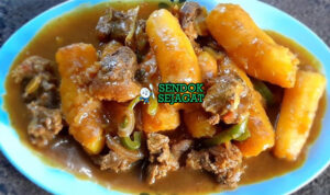 Matoke ya nyama khas Uganda siap saji: pisang plantain rebus empuk lembut dalam kuah tomat merah kental, daging sapi empuk, tabur daun bawang atau peterseli, disajikan dengan nasi putih atau posho, terlihat hangat gurih menggoda