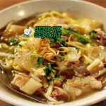 Mie kocok khas Bandung siap saji: mangkuk mie kuning kenyal dengan kuah kaldu sapi bening gurih, kikil sapi empuk kenyal, tahu goreng, telur rebus, tauge segar, bawang goreng, dan kerupuk, terlihat hangat menggoda dengan uap mengepul