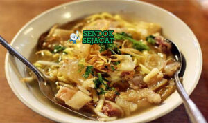 Mie kocok khas Bandung siap saji: mangkuk mie kuning kenyal dengan kuah kaldu sapi bening gurih, kikil sapi empuk kenyal, tahu goreng, telur rebus, tauge segar, bawang goreng, dan kerupuk, terlihat hangat menggoda dengan uap mengepul