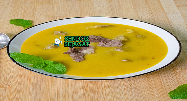 Mangkuk mtori khas Tanzania berisi sup kental kuning keemasan, potongan daging sapi empuk, pisang plantain tumbuk lembut, taburan bawang goreng dan daun ketumbar segar