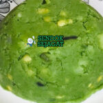 Mukimo khas Kenya siap saji: pure kentang lembut kental berwarna kuning pucat, campur kacang hijau manis, jagung manis kuning, bawang goreng tabur, disajikan dengan daging rebus dan sayur hijau, terlihat hangat menggoda di piring besar