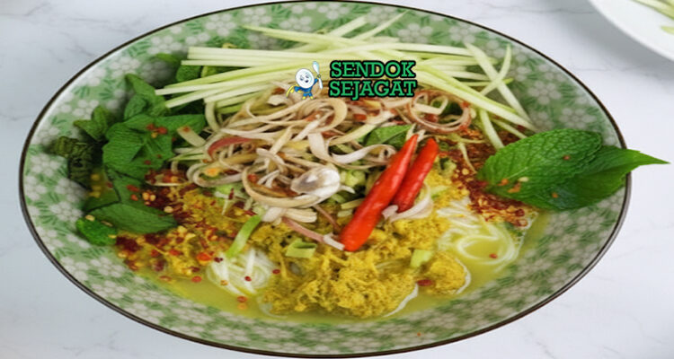 Nom Banh Chok khas Kamboja disajikan hangat dengan mie beras, kuah santan ikan kuning kehijauan, sayur mentah renyah, dan daun harum