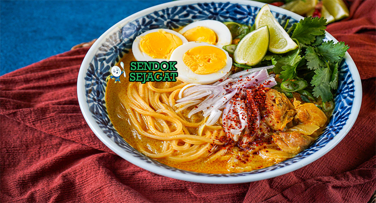 Ohn No Khao Swè khas Myanmar siap saji: mangkuk mie kuning kenyal dengan kuah santan kuning kental gurih, ayam suwir lembut, telur rebus, tauge segar, bawang goreng, daun bawang iris, dan kerupuk, terlihat hangat menggoda dengan uap mengepul