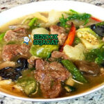 Mangkuk Or Lam khas Laos berisi sup daging sapi empuk, terong bulat, kacang panjang, jamur kuping, taburan dill dan kemangi Laos, disajikan dengan nasi ketan hangat