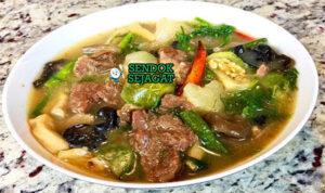 Mangkuk Or Lam khas Laos berisi sup daging sapi empuk, terong bulat, kacang panjang, jamur kuping, taburan dill dan kemangi Laos, disajikan dengan nasi ketan hangat