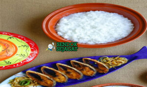 Mangkok Panta Ilish khas Bangladesh dengan nasi fermentasi dingin, ikan hilsa goreng renyah, bawang iris, cabai hijau, dan jeruk nipis, tampak segar gurih menggugah selera