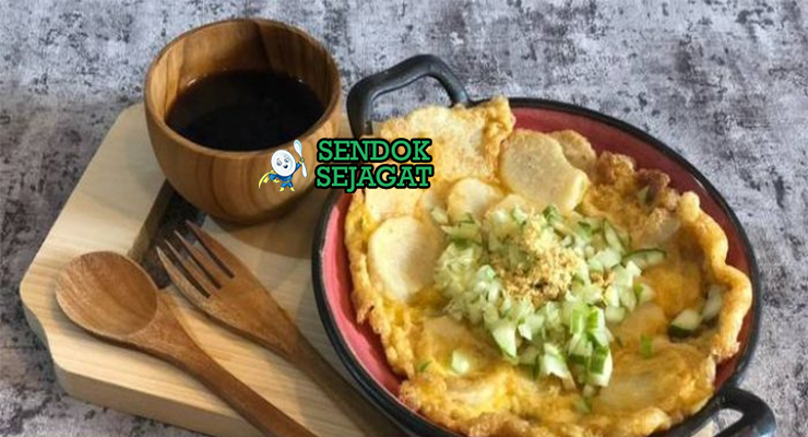 Potongan pempek lenggang khas Palembang yang lembut bertekstur fluffy, disajikan dengan cuko hitam pedas, irisan timun segar, bawang goreng, dan ebi sangrai