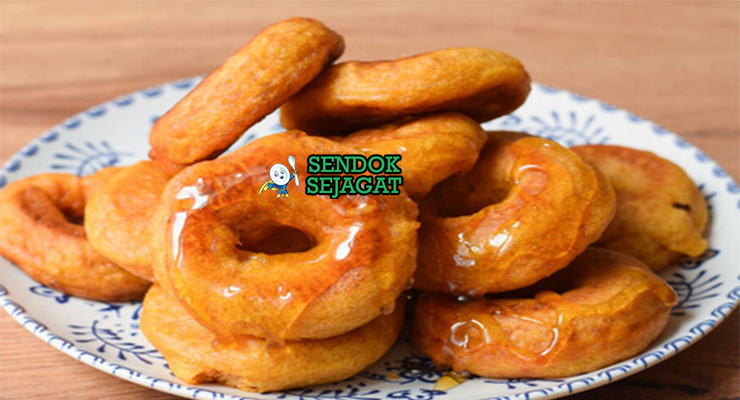 Tumpukan Picarones khas Peru yang renyah keemasan, direndam sirup chancaca mengkilap, tampak manis gurih menggugah selera